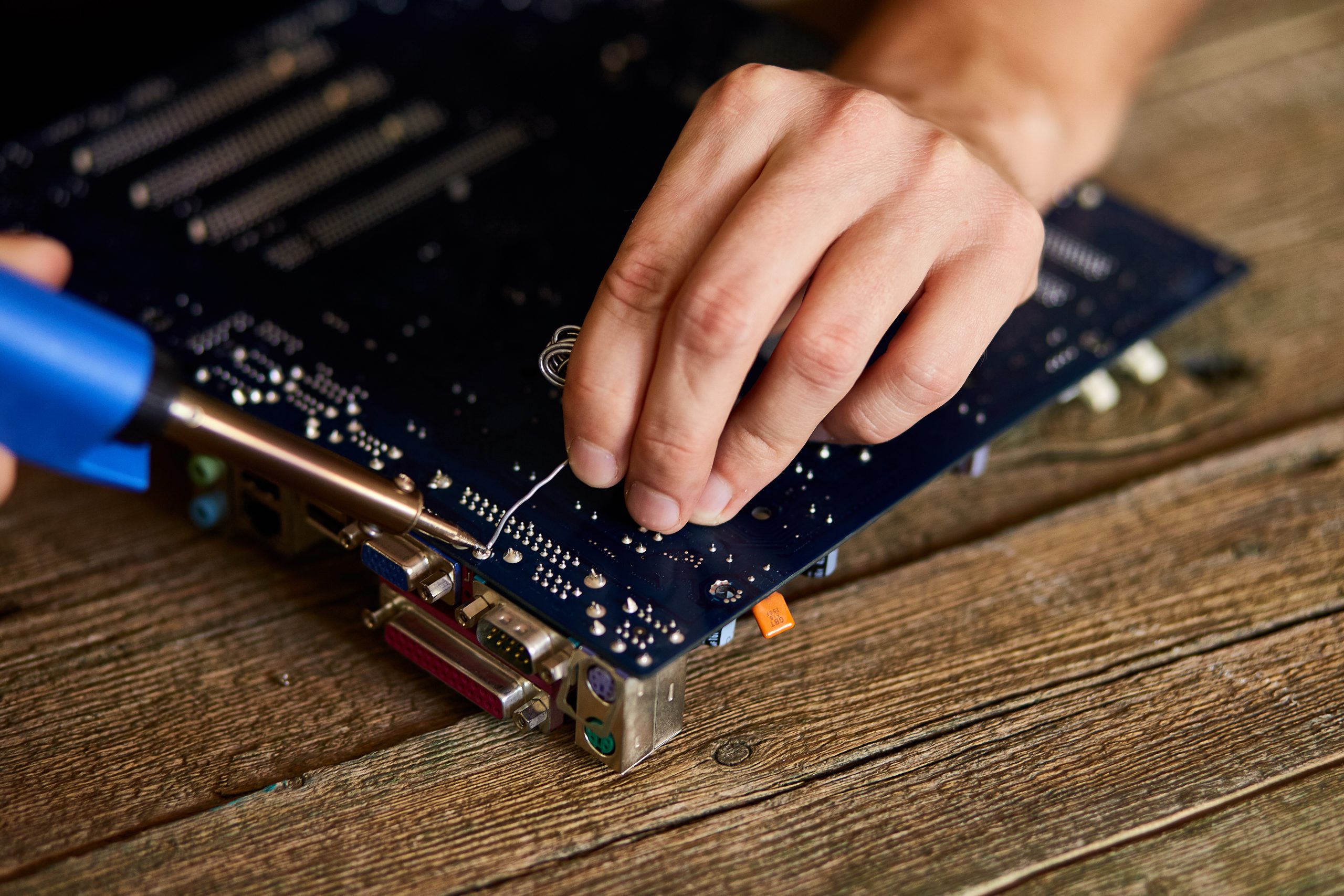 Engineer or technician repair electronic circuit board with soldering iron. Man hands soldiers computer circuit board using soldering iron. Copy space.